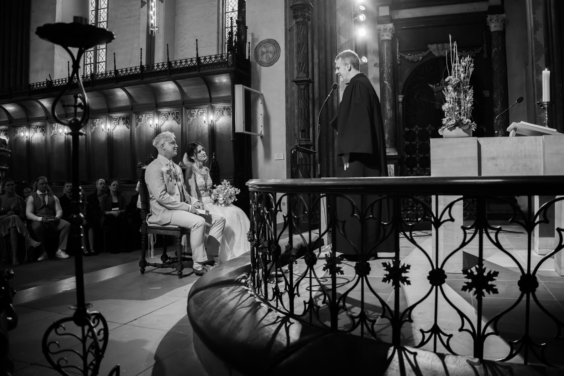 Brautpaar sitzt während der kirchlichen Trauung im Dom, im Hintergrund der Pastor am Altar